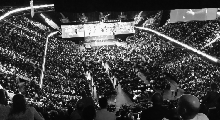 imagem de um grande auditório, com pessoas assistindo a um evento